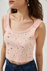 Musculosa rosa con estampado de margaritas blancas y amarillas, de bretel ancho, corte al cuerpo y cuello redondo.