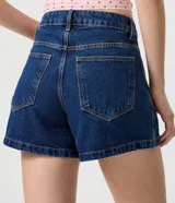 Short de jean azul oscuro con corte evasé, bolsillos delanteros y traseros, pasacintos en la cintura y cierre frontal con botón y cremallera. Incluye un pequeño aplique metálico de corazón.