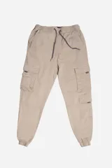 Pantalón cargo color beige con cintura elástica y cordón ajustable. Presenta múltiples bolsillos laterales con solapa y puños elásticos en los tobillos.