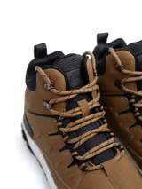 Bota de trekking de caña alta modelo Alpes, confeccionada en ecocuero marrón con refuerzos negros en puntera y talón. Cuenta con cuello acolchado, ojalillos metálicos, cordones bicolores y suela dentada antideslizante con entresuela blanca.