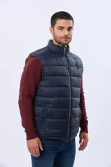 Chaleco reversible capitoneado de corte estándar, con cuello alto, cierre frontal de cremallera y botones a presión. Cuenta con bolsillos laterales y un bolsillo vertical en el pecho.