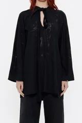 Camiseta larga negra con estampado abstracto, cuello mao con lazo, corte recto y mangas largas anchas.