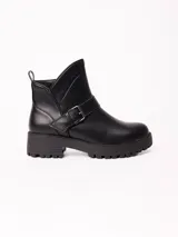 Bota corta de cuero sintético color negro, con suela track de goma y detalle de tira con hebilla metálica en el tobillo.