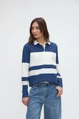 Remera polo de manga larga de algodón lavado, con diseño de rayas horizontales anchas en azul y blanco, cuello y cartera de botones en color blanco, y pequeños tajos laterales.