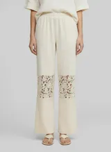 Pantalón de tiro medio color avena (oatmeal) con cintura elastizada y calce regular. Presenta paneles de encaje floral calado en la parte inferior de ambas piernas.