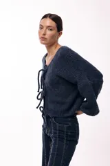 Saco tejido de punto color azul, con escote en V y cierre frontal mediante lazos. Presenta mangas largas amplias con puños ajustados y un calce relajado.