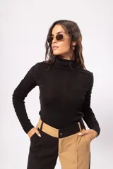 Polera negra de manga larga con cuello alto y detalle de drapeado en las mangas. Confeccionada en tela stretch suave con leve brillo.