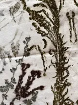 Mantel rectangular de algodón color crudo con estampado botánico en tonos marrones y verdes.