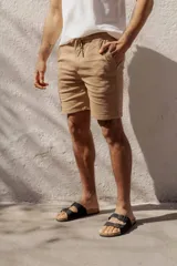 Bermuda de algodón color beige, con elástico y cordón ajustable en la cintura, y bolsillos laterales.