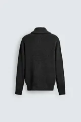 Chaqueta de punto con textura acanalada, cuello subido y cierre frontal completo con cremallera metálica. Presenta un corte relajado y acabados en rib en puños y ruedo.