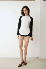 Remera de manga larga estilo raglan, color verde militar, con cuello redondo y dobladillo inferior curvado.