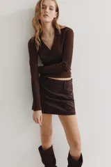 Top de manga larga color marrón oscuro, confeccionado en tejido de punto acanalado. Presenta un cuello camisero que se abre en un escote pronunciado en V.