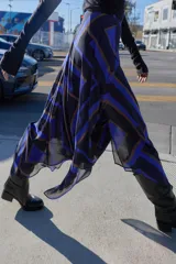 Falda midi de corte asimétrico con diseño cruzado en el delantero y aberturas. Presenta un estampado geométrico en tonos azul, negro y beige, con forro interior y cierre trasero con cremallera oculta.
