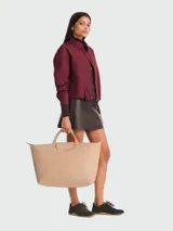 Bolso de mano tipo tote de la línea Le Pliage One de Longchamp, en color bordó. Presenta un diseño minimalista con cierre de cremallera superior, solapa con botón a presión y asas cortas de cuero.
