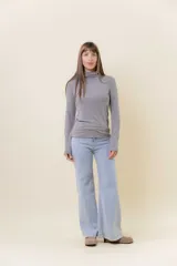 Polera blanca de manga larga y calce al cuerpo, confeccionada en tejido suave, liviano y elástico, con cuello alto.