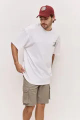 Remera oversize blanca de manga corta, con corte amplio y estampa gráfica pequeña en el pecho.