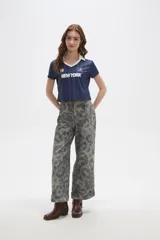 Pantalon de jean de corte ancho y tiro alto, con diseño estampado animal print en tonos grisáceos. Presenta pinzas en la cintura y ruedo con doblez.