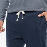 Conjunto de pijama de dos piezas compuesto por una camiseta de manga larga a rayas horizontales finas con bolsillo frontal y un pantalón largo de color azul marino con puños elásticos en los tobillos.