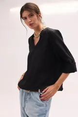 Blusa de lino color lila, de corte relajado y mangas largas amplias, con escote en V y ruedo curvo.