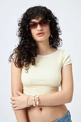 Top corto negro de punto acanalado con escote redondo, mangas cortas y ribetes blancos en cuello y mangas.