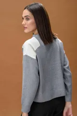 Sweater de punto color beige con cuello redondo y detalles de parches en cuero sintético blanco en los hombros. Presenta mangas largas con puños acanalados y un corte holgado.