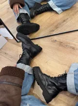 Botas de cuero negras con cordones, suela track y cierre lateral.