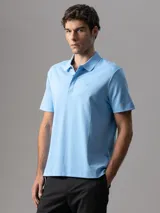 Chomba de manga corta Calvin Klein confeccionada en algodón interlock, con cuello clásico y cierre frontal de botones. Presenta un diseño liso en color celeste con el logo de la marca bordado sutilmente en el pecho.