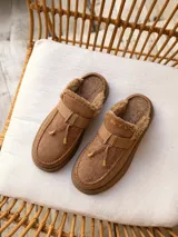 Suecos de símil gamuza color beige, con interior forrado en corderito sintético, plataforma y detalle de tira frontal con cordones y punteras metálicas.
