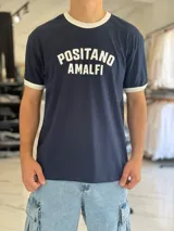 Remera oversize azul marino de algodón pesado con cuello redondo y ribetes blancos en el cuello y las mangas. Cuenta con un estampado frontal en color blanco con las palabras POSITANO AMALFI.