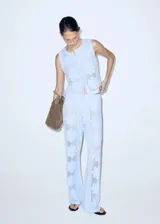 Pantalón tejido de punto celeste con diseño calado de flores, de corte recto y tiro medio con cintura elástica.