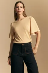Remera de rib color beige, con cuello redondo y mangas cortas amplias con leve frunce en los hombros. Confeccionada en tejido elastizado de textura acanalada.