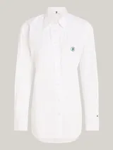 Camisa blanca de algodón orgánico, corte regular entallado, cuello inglés, mangas largas con puño, bajo más largo en la parte trasera y logo TH bordado en el pecho.