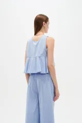 Musculosa de algodón color celeste, con cuello redondo y detalles bordados en tono blanco con diseño de broderie en la parte frontal. Cuenta con cordones laterales para ajustar.