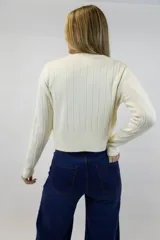 Buzo beige de tejido de punto con textura acanalada vertical, cuello redondo y mangas largas.