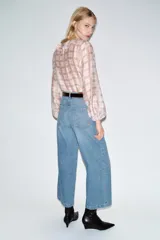 Blusa de manga larga abullonada con puños elásticos, cuello redondo con volantes y detalle de cordón ajustable en el escote pico. Presenta un estampado a cuadros en tonos blanco y rosado/marrón claro.