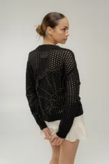 Buzo tejido calado en ceridó, color crudo, con bordados característicos del mar, detalles a contratono y escote en V.