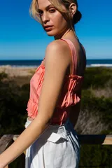 Crop top color salmón, fruncido con elásticos y tirantes finos. Detalles de volados en los bordes superior e inferior.