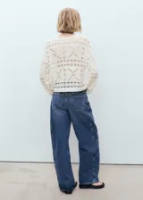 Jersey de punto calado con diseño geométrico, cuello redondo y manga larga. Presenta un corte oversize y acabado ligero.