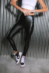 Calzas negras de bengalina engomada brillante, tiro alto y botamanga irregular.