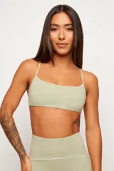 Conjunto deportivo de dos piezas en color verde pistacho, compuesto por un top de tirantes finos con escote recto y una calza larga de tiro alto con detalles de líneas en contraste.