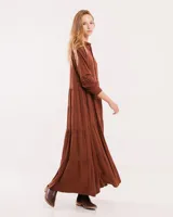 Vestido largo color marrón con cuello camisero, manga larga con puños elásticos y falda escalonada con volados.