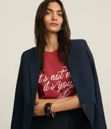 Remera de algodón color ladrillo con cuello redondo y mangas cortas. Estampado frontal con la frase "It's Not Me It's You" en letras cursivas blancas.