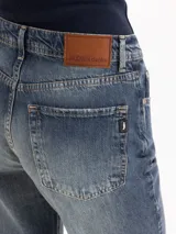 Jeans Fred de tiro alto y corte recto, con diseño ligeramente acampanado hacia el dobladillo, lavado azul medio con efecto desgastado y detalles deshilachados en los tobillos.