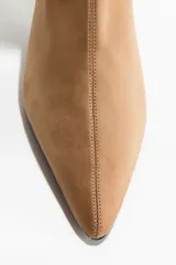 Botines de caña media con diseño elástico entallado, punta fina y taco fino forrado.