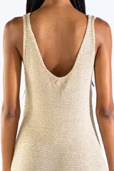 Vestido largo de punto abierto con sutil brillo dorado, escote en V y diseño sin mangas con detalles de flecos en el ruedo.