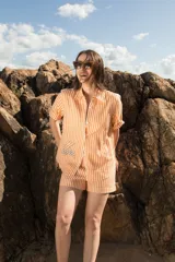Camisa de manga corta oversize en lino rayado, con cuello camisero, cierre frontal con botones y bordado playero en el frente.