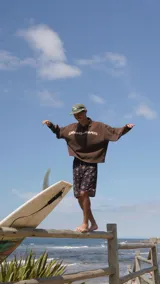 Buzo de tejido de punto color marrón con cuello polo, manga larga y estampado frontal con el nombre de la marca en color crema.