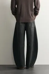 Jeans de denim de algodón color gris con efecto lavado, de corte relaxed barrel fit y tiro medio. Presenta diseño amplio con pinzas en las rodillas y costuras curvas, cierre frontal con botones y cinco bolsillos tradicionales.