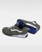 Zapatillas Vans Rowley XLT de color gris oscuro, con la franja lateral Sidestripe en blanco, pasador de cordones con etiqueta de la marca y detalles en azul. Presentan diseño robusto inspirado en el skate de los años 90 y 2000, con lengüeta acolchada y suela combinada en blanco y negro.