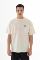 Remera color crudo de algodón con estampado azul de la banda Oasis, con logo, dibujos de los integrantes y referencias a sus canciones.